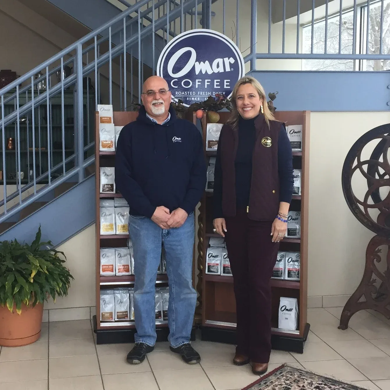 two people posing in front of omar coffee display with product shelving., omar coffee company, newington