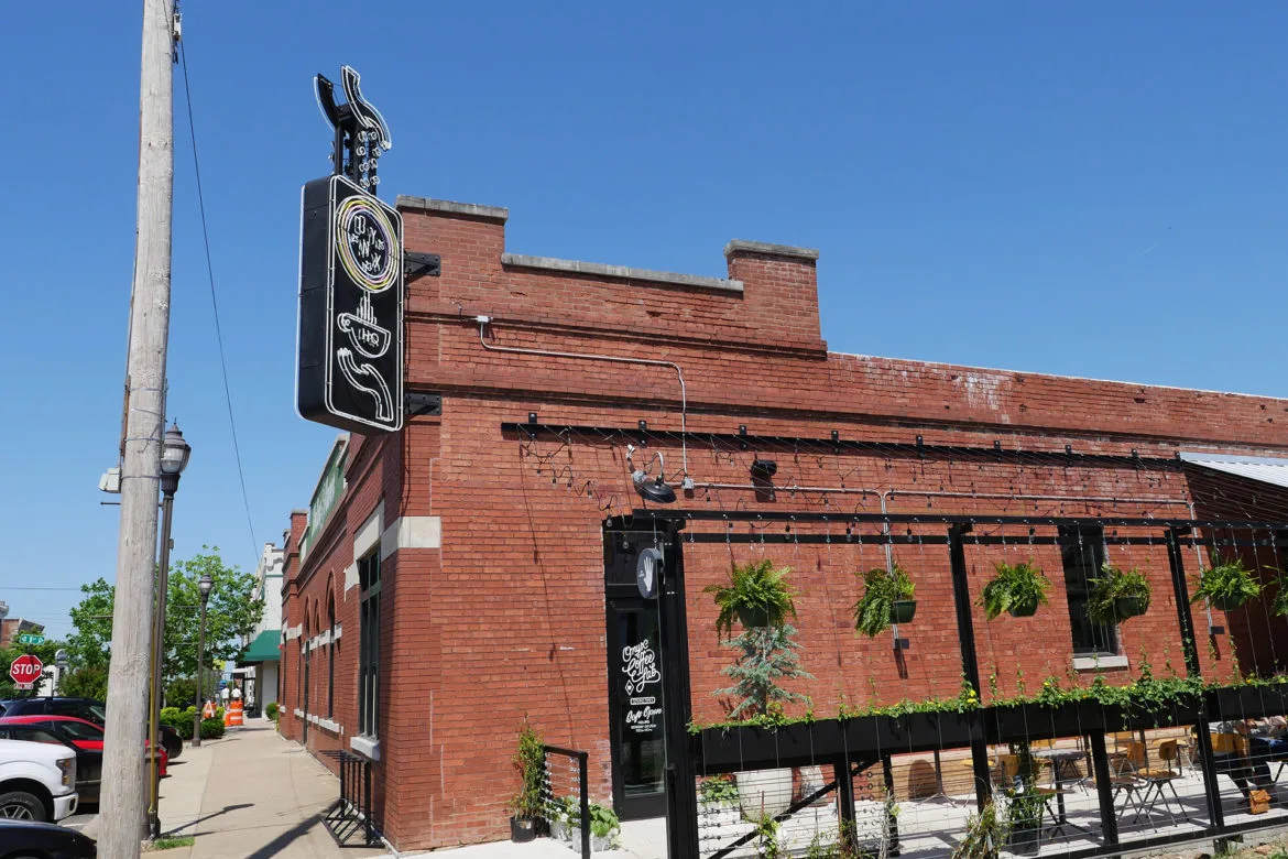 red brick building with ornate signage and hanging plants on storefront., onyx coffee lab, rogers