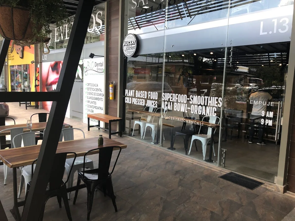 health-focused juice bar storefront with outdoor seating and operating hours displayed., oromo café librería, cali