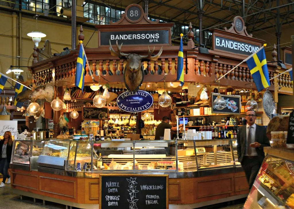 banderssons market stall with swedish flags, taxidermied deer head, and food displays., östermalms food hall, stockholm