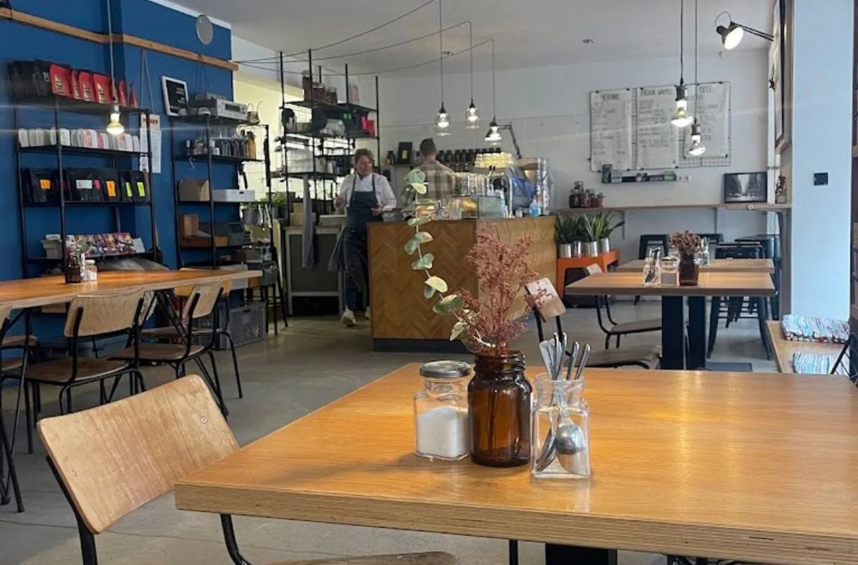 modern café interior with wooden tables, blue shelving, and counter service area., pacandé kaffeerösterei kg, munich