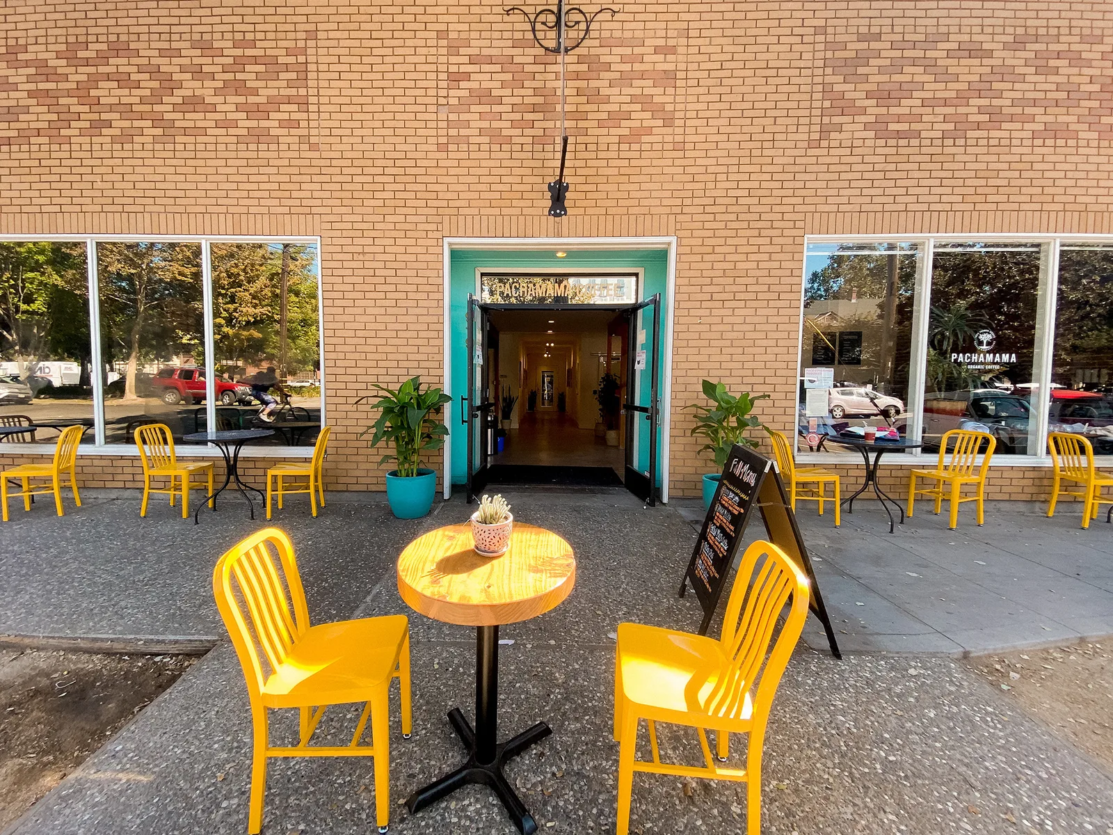 brick storefront with turquoise door, yellow chairs, outdoor patio seating., pachamama coffee, sacramento