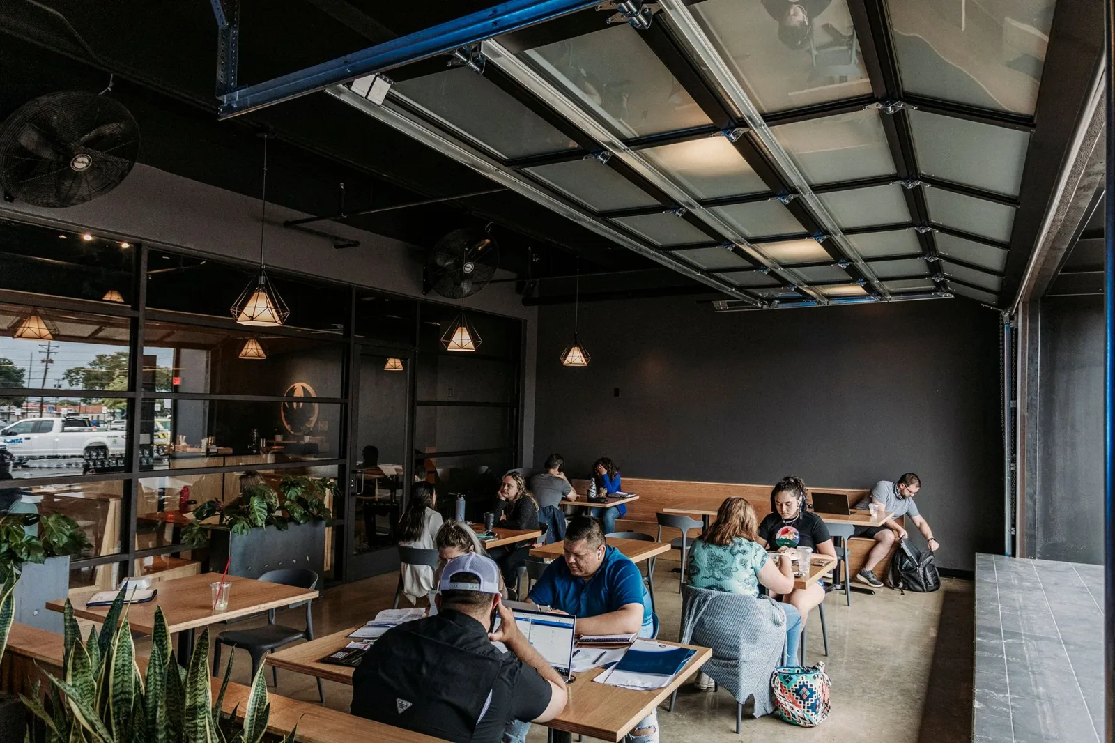 modern café interior with wooden tables, skylights, pendant lamps, and working patrons., palace coffee company, amarillo