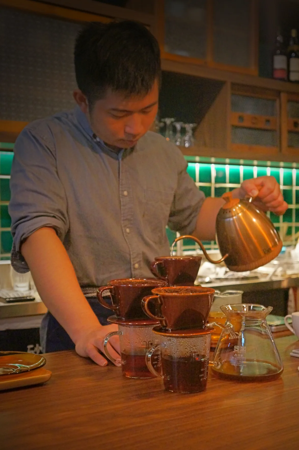 person pouring hot water from kettle into brown ceramic cups for tea service., pallas cafe, taipei
