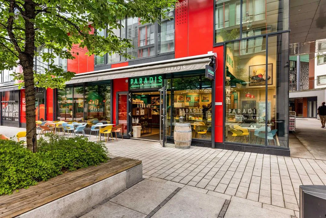 modern storefront with red facade, outdoor seating, and green landscaping., paradis gelateria tjuvholmen, oslo