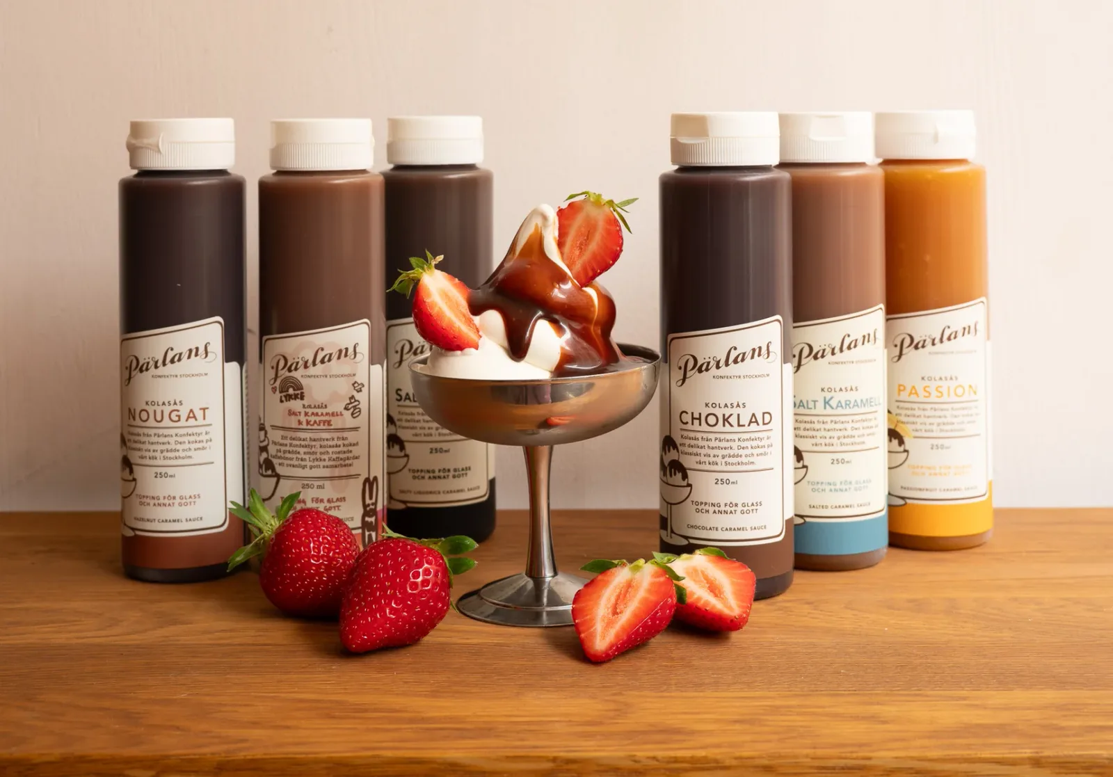 parlans gourmet sauce bottles displayed with fresh strawberries and a dessert cocktail., pärlans konfektyr, stockholm