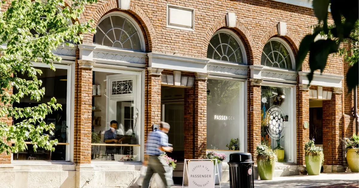 brick storefront with arched windows, green ivy, and pedestrians passing by cafe entrance., passenger / necessary coffee, lan