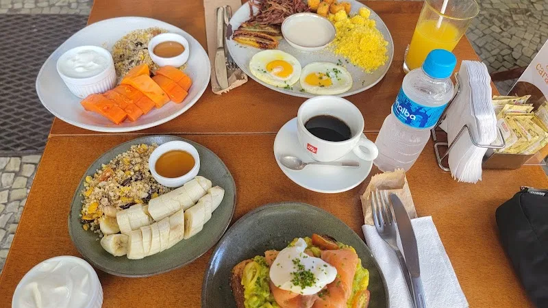 breakfast spread with eggs, fruit, pastries, coffee, and juice on wooden table., pendê café, rio de janeiro