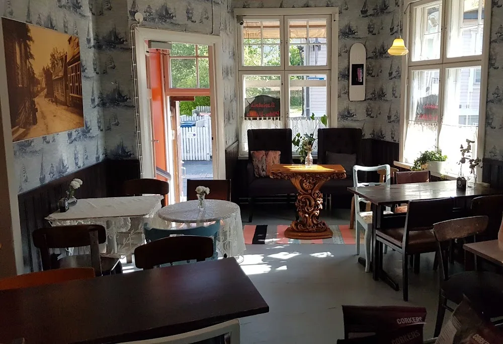 victorian-style café interior with patterned wallpaper, dark furniture, and ornate tables., pikku-vallila, helsinki