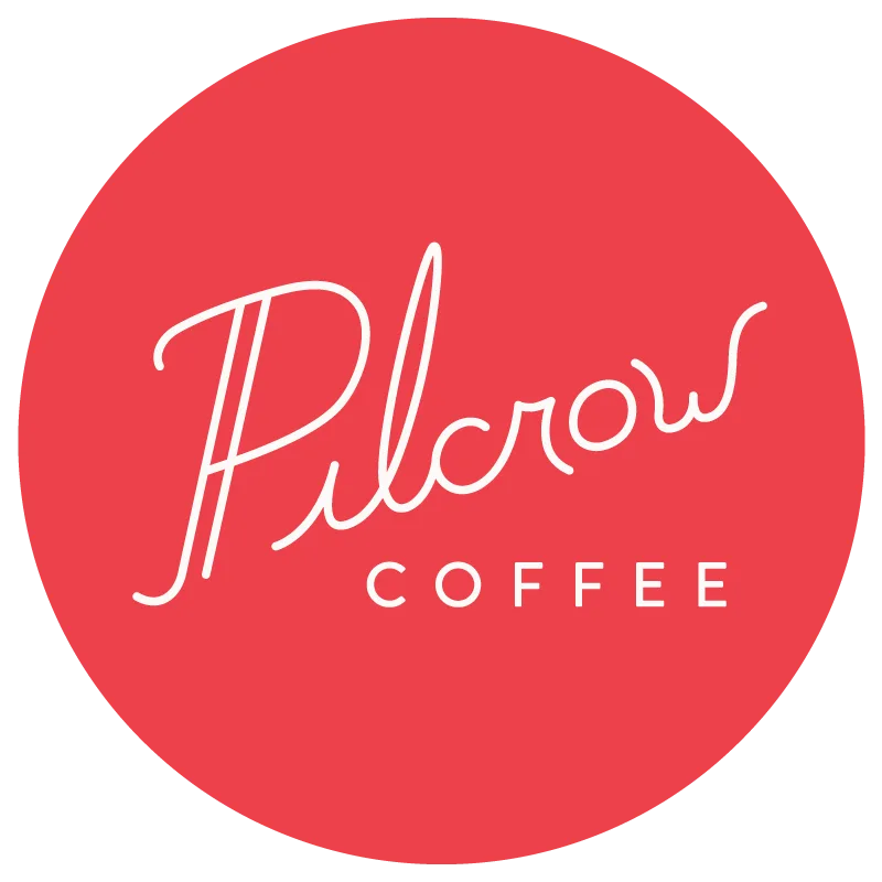 red circular logo with white script text reading "pilcrow coffee"., pilcrow coffee, milwaukee