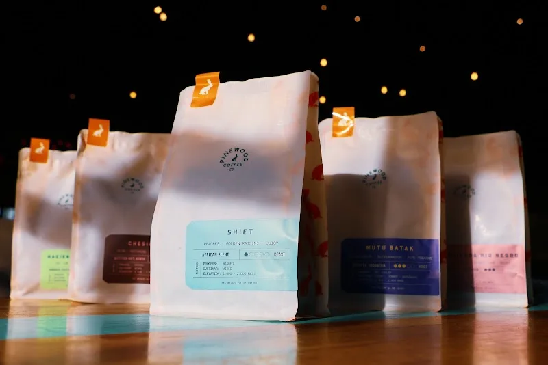 coffee bags with branded labels displayed on reflective surface with golden bokeh lights., pinewood coffee co., franklin