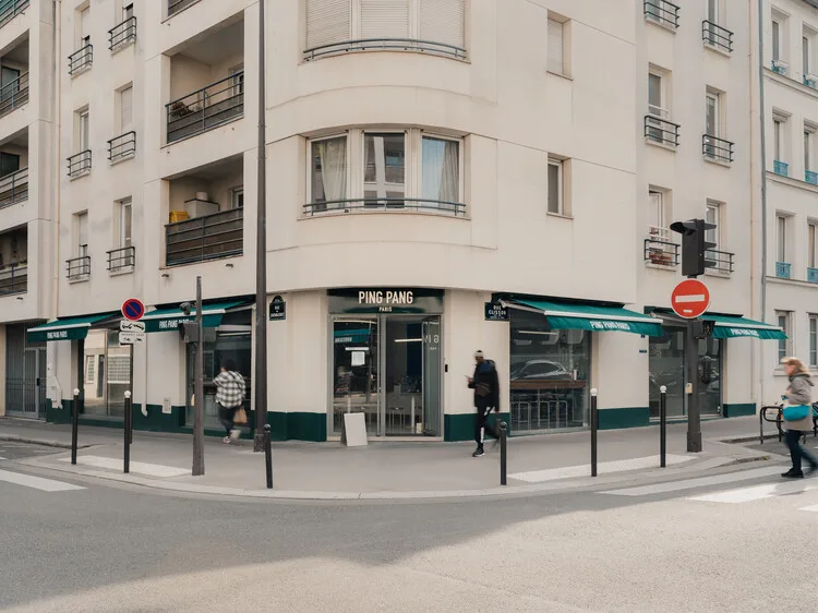 corner storefront with "ping pang" signage beneath cream-colored residential building., ping pang paris, paris