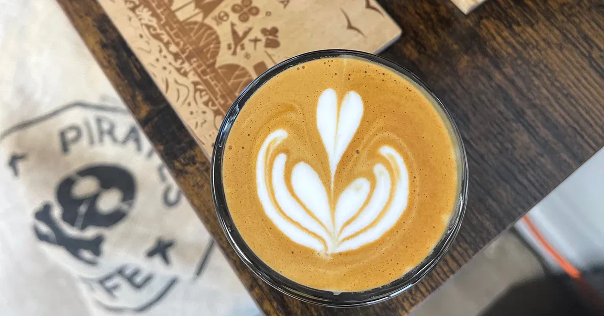 latte with heart-shaped latte art on wooden table near café napkin., pirates of coffee, mississauga