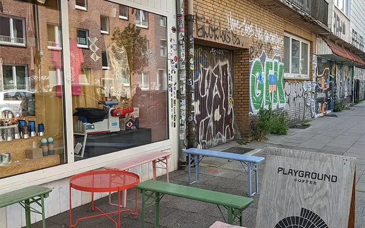 urban street scene with colorful furniture, storefronts, and graffiti-covered brick walls., playground coffee st. pauli, hamb