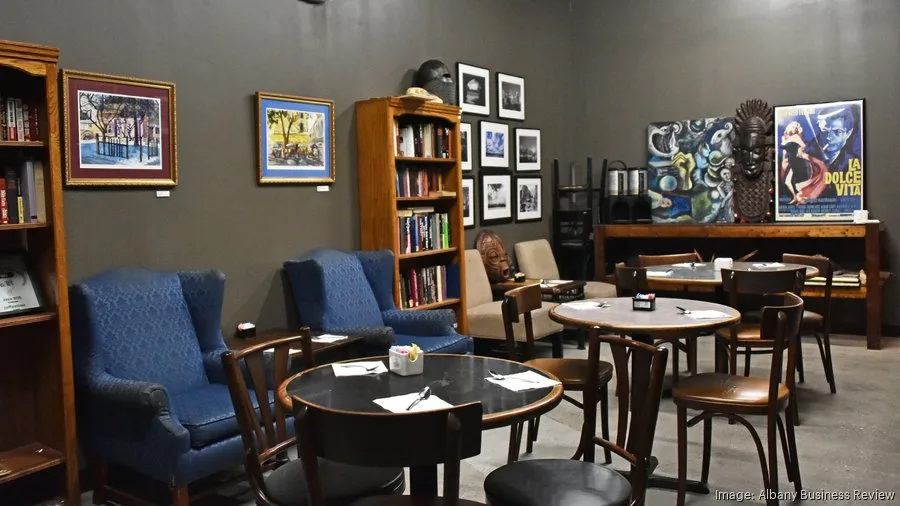 modern lounge with blue chairs, round tables, wooden bookshelves, and framed artwork., professor java's coffee sanctuary, new