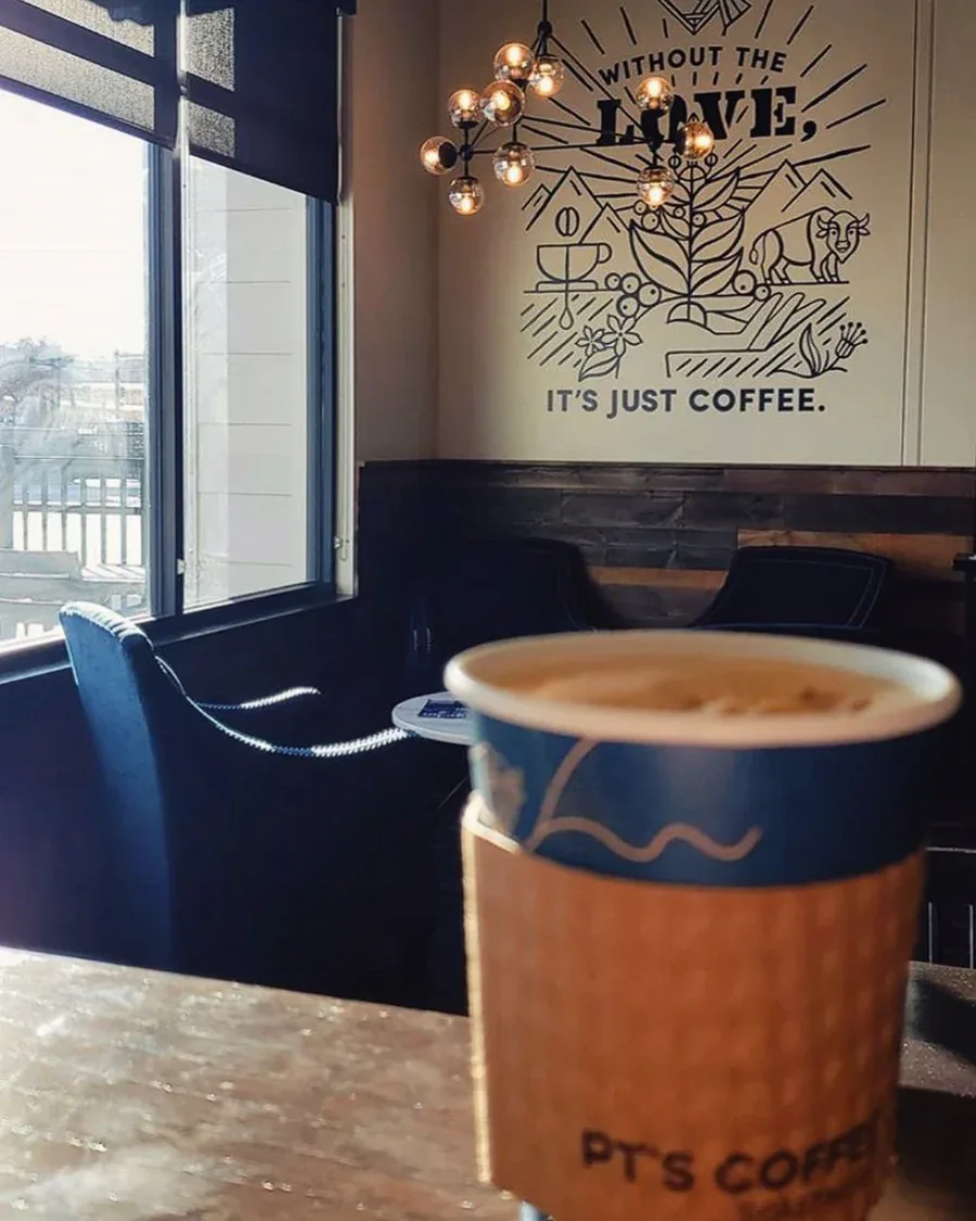 coffee cup with latte art in modern café with wall mural and pendant lighting., pt's coffee, topeka