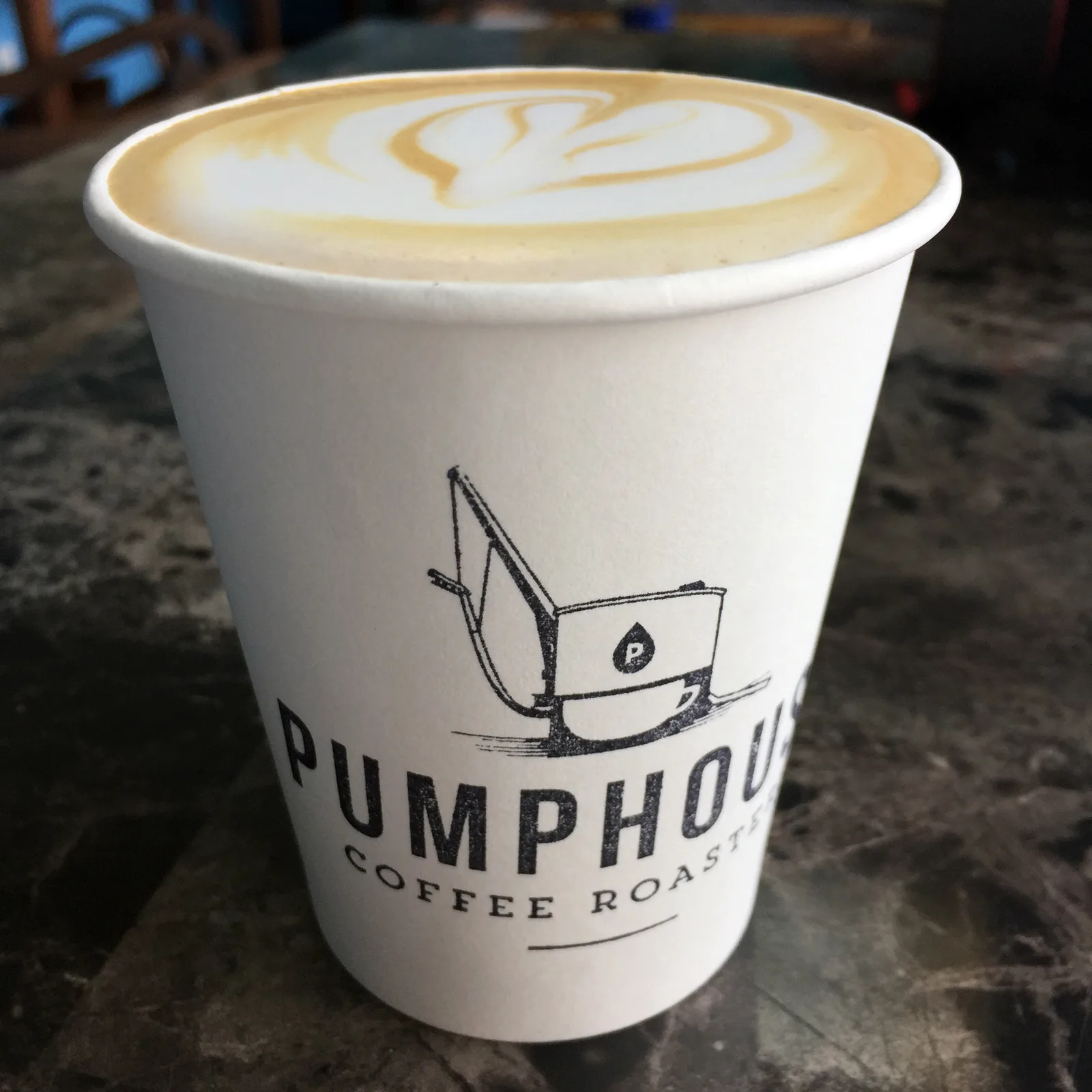 latte with latte art in pumphouse coffee roastery cup on dark countertop., pumphouse coffee roasters, miami