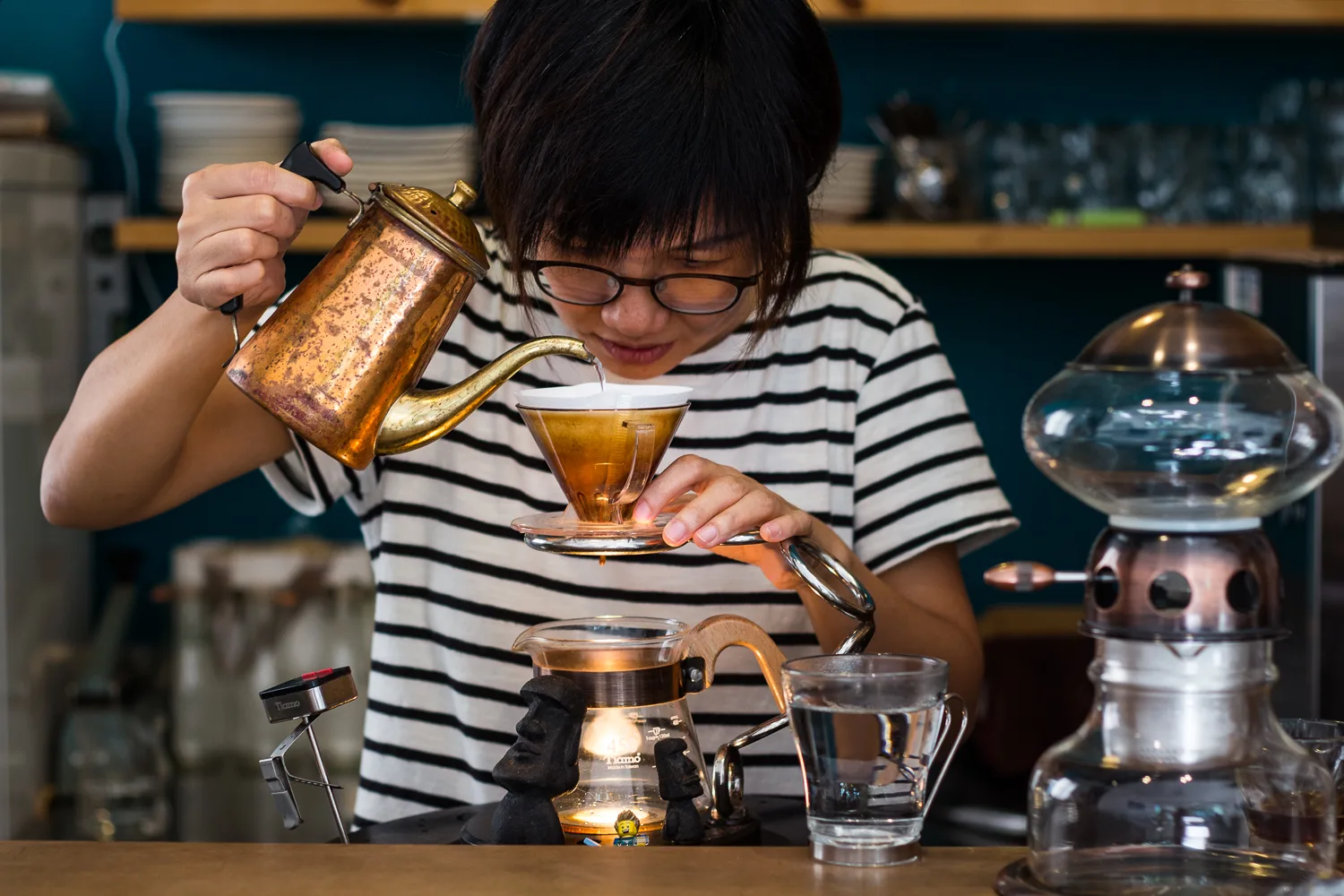 woman in striped shirt pouring hot water into tea cup at cafe counter., pure coffee, taipei