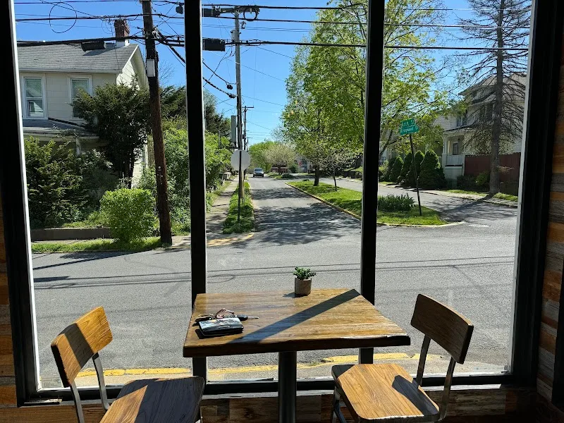 table and chairs by large windows overlooking quiet residential street., quantum bean coffee, morgantown