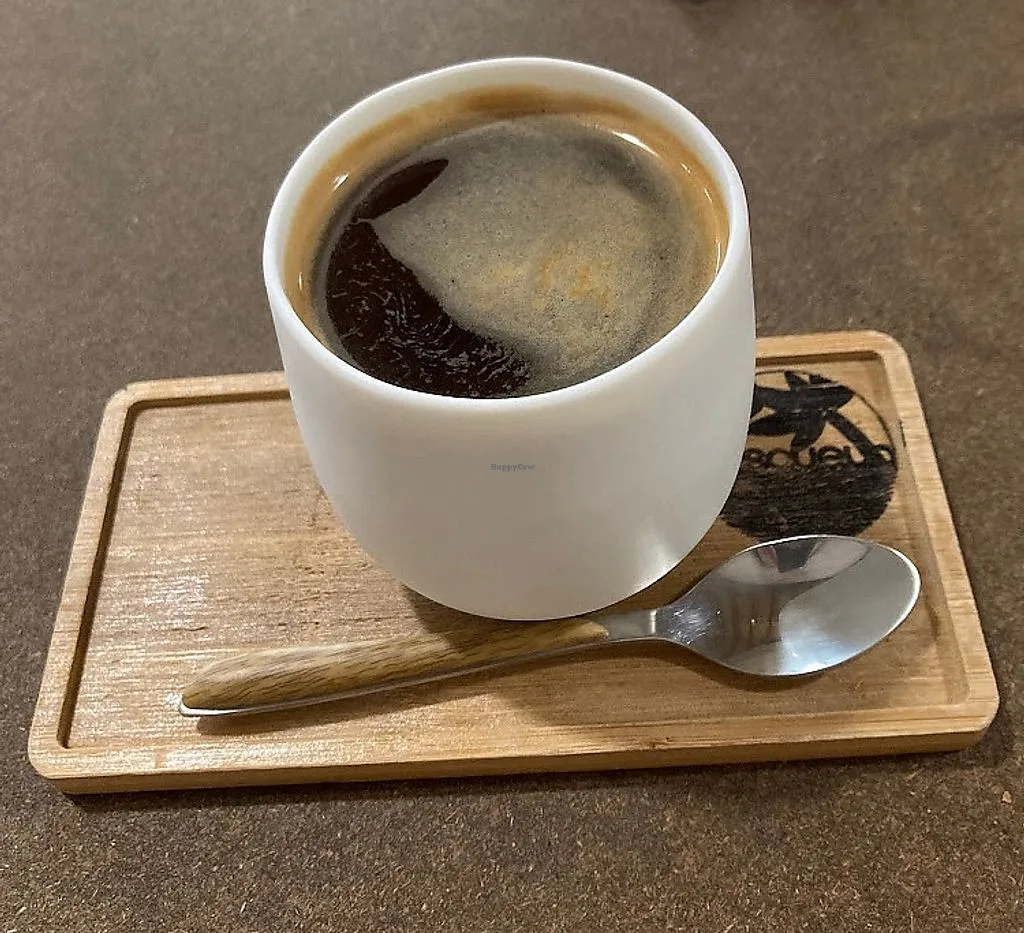 white ceramic cup of black coffee on wooden coaster with spoon., quisqueya, madrid
