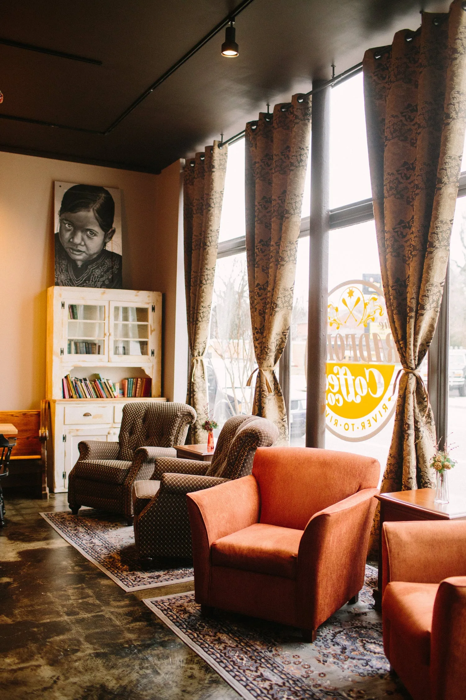 warm lounge with orange chairs, patterned curtains, and large windows., radford coffee company, blacksburg