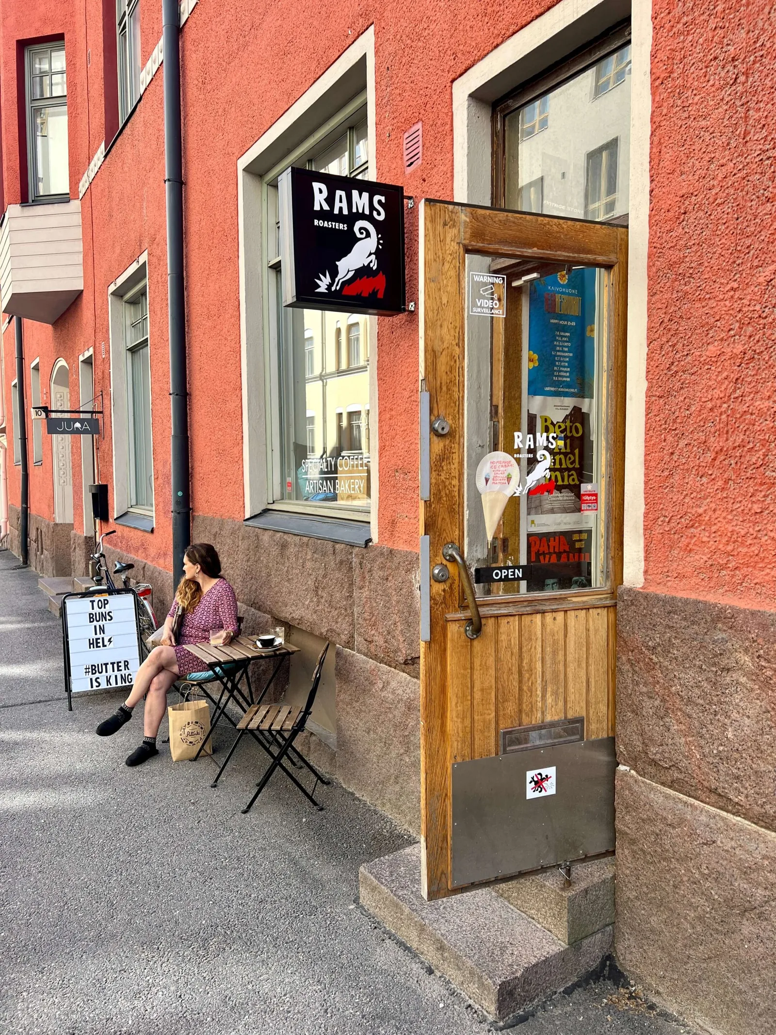woman sitting outside rams roastery café on european street corner., rams roasters, helsinki