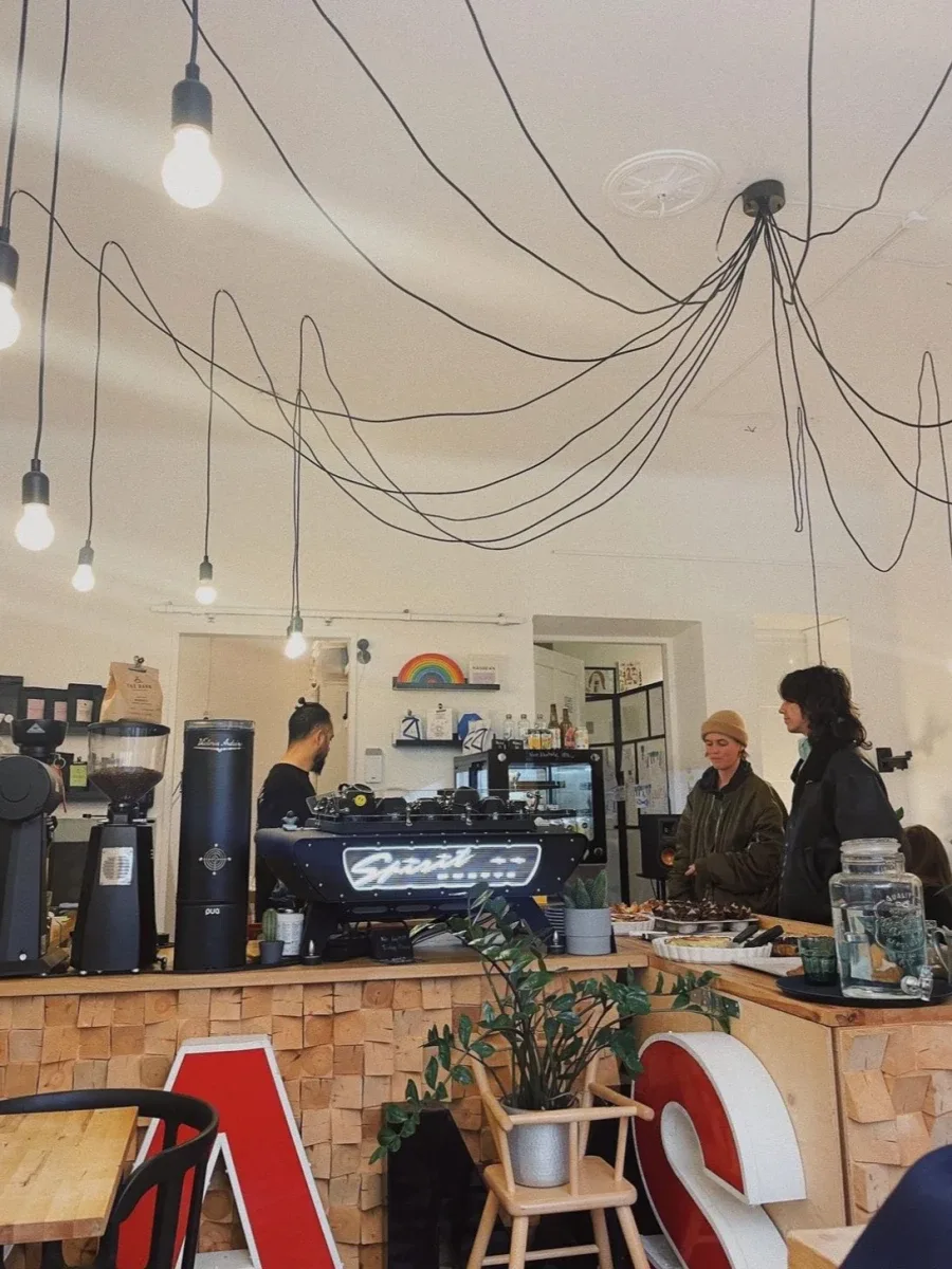 modern café interior with pendant lighting, espresso machine, and customers at wooden counter., rams roasters, helsinki