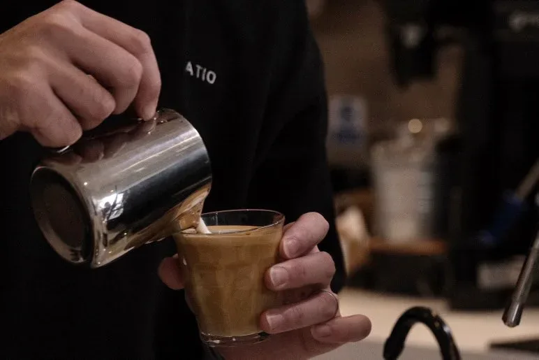 barista pouring steamed milk into espresso shot, creating coffee beverage., ratio coffee (no food), crows nest
