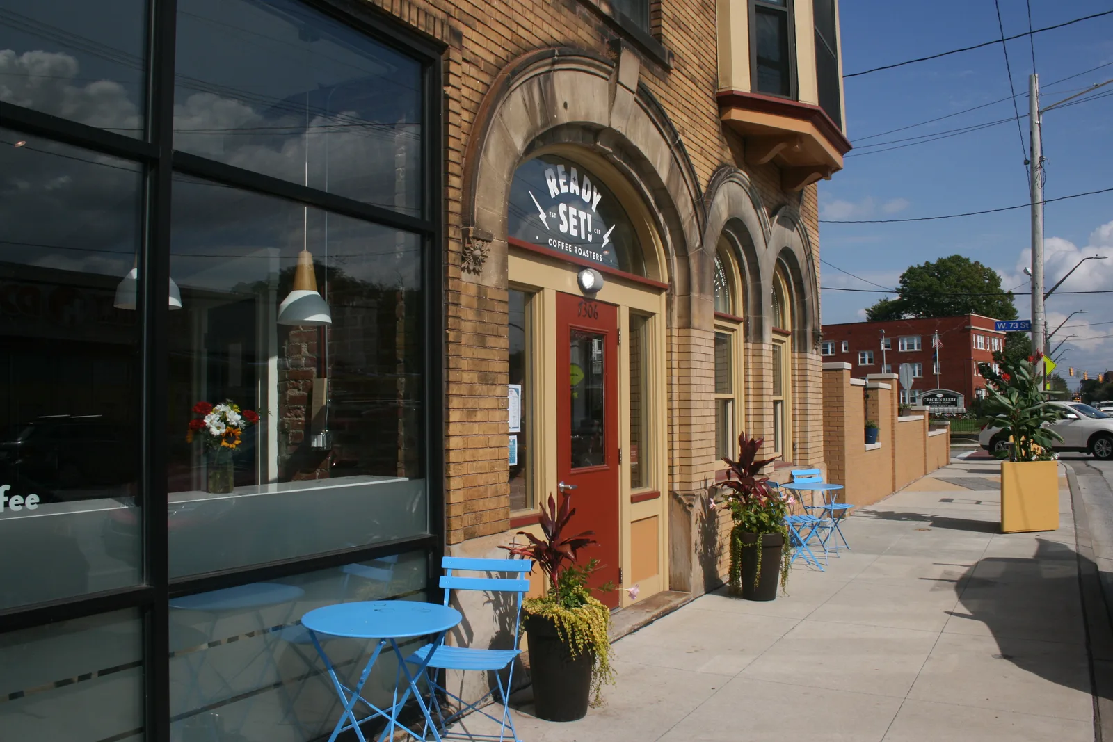 coffee shop storefront with blue patio seating and brick architecture., ready set! coffee roasters, cleveland