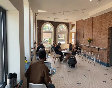 interior space with people seated at tables, exposed brick walls, and natural light from arched windows., ready set! coffee r