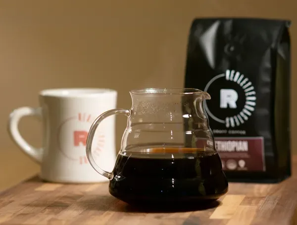 coffee carafe, mug, and bag of ethiopian roasted beans on wooden surface., red letter roasters, baraboo