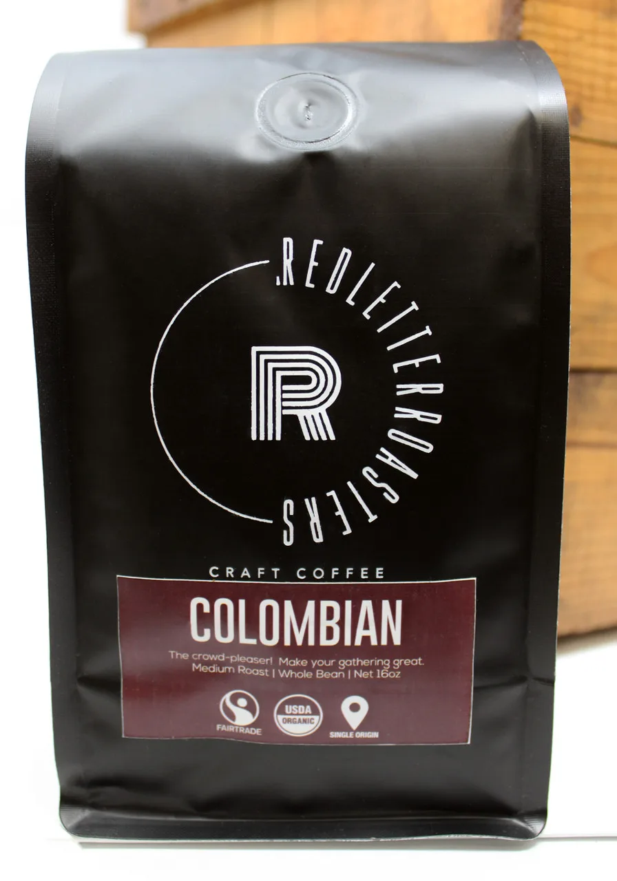 black coffee bag with circular logo, colombian label, and fair trade certifications displayed., red letter roasters, baraboo