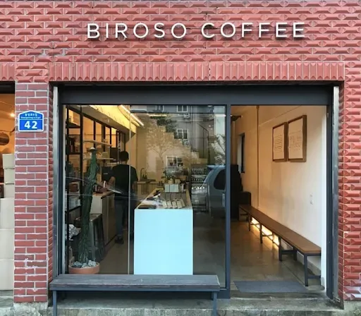 biroso coffee storefront with brick facade, large window display, and minimalist interior design., reflect coffee roasters, s
