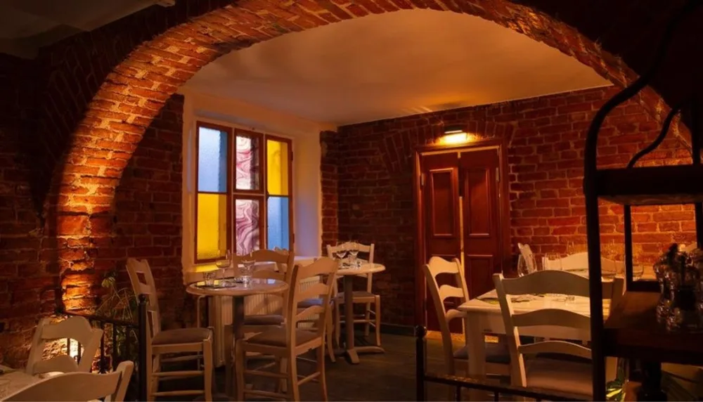 rustic brick restaurant interior with arched doorway, wooden chairs, and warm lighting., restaurant gran delicato, helsinki