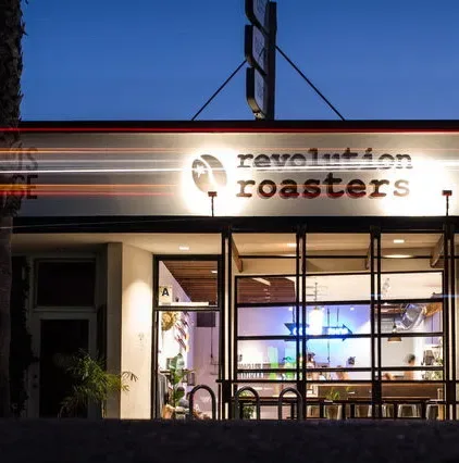 revolution roasters storefront illuminated at dusk with large windows and signage., revolution roasters, san diego