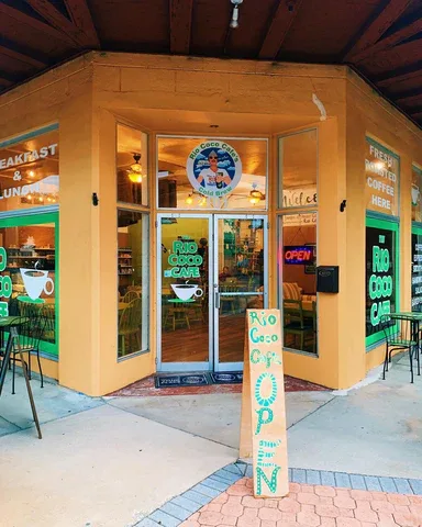 corner café with yellow walls, green neon signs, and glass doors entrance., rio coco beans, vero beach