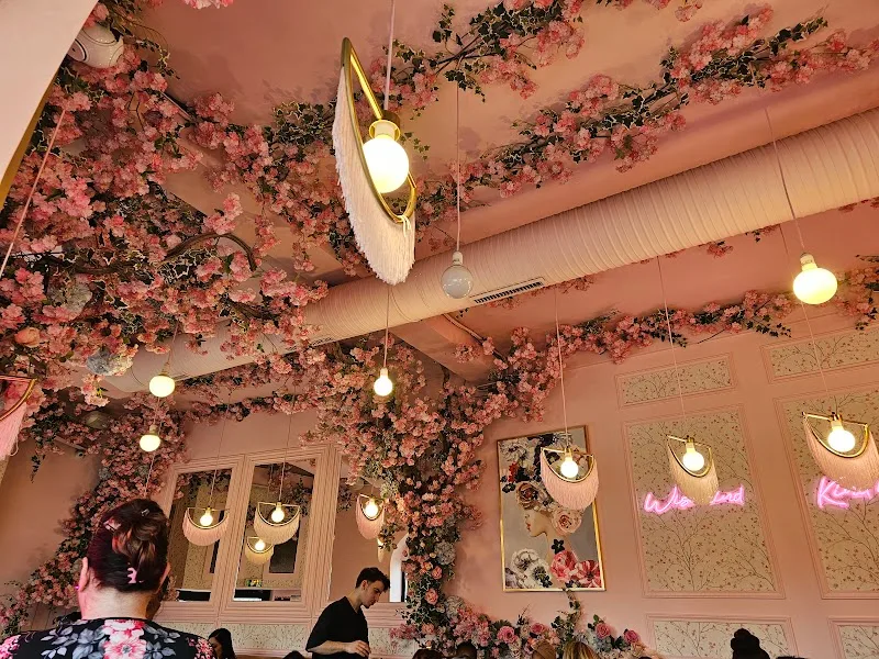 luxurious pink interior with cascading floral installations and hanging brass pendant lights., riverose, paris
