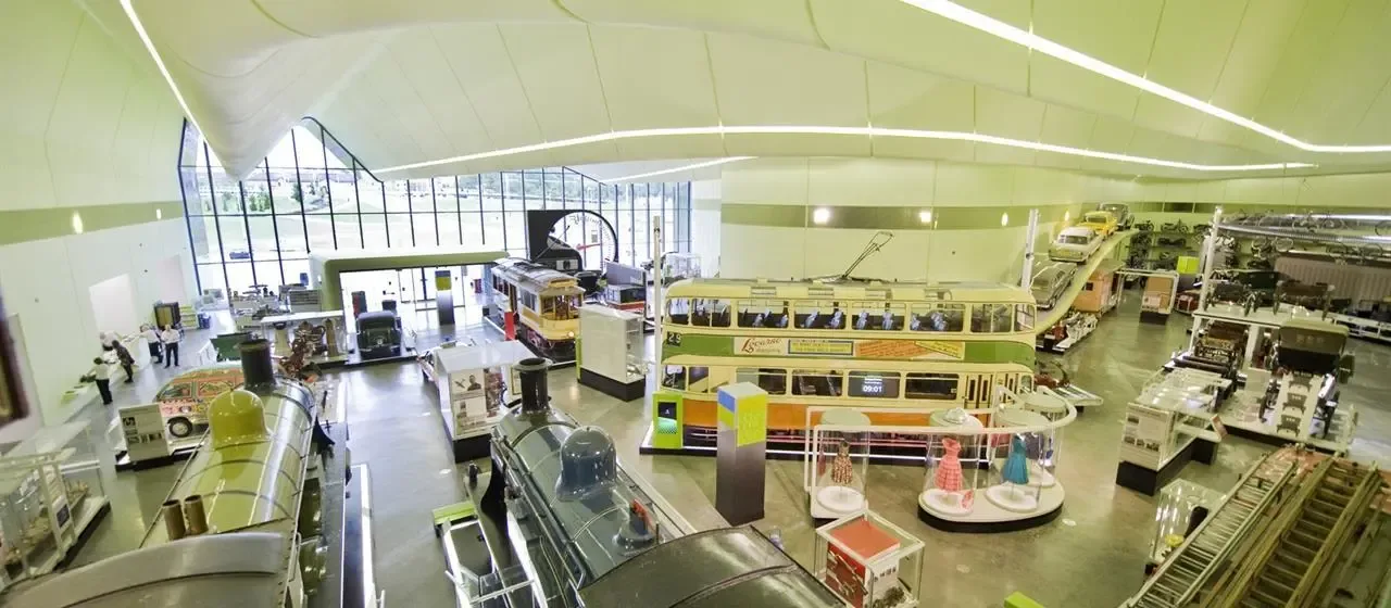 museum exhibition hall displaying vintage trains, buses, and transportation vehicles indoors., riverside museum, glasgow