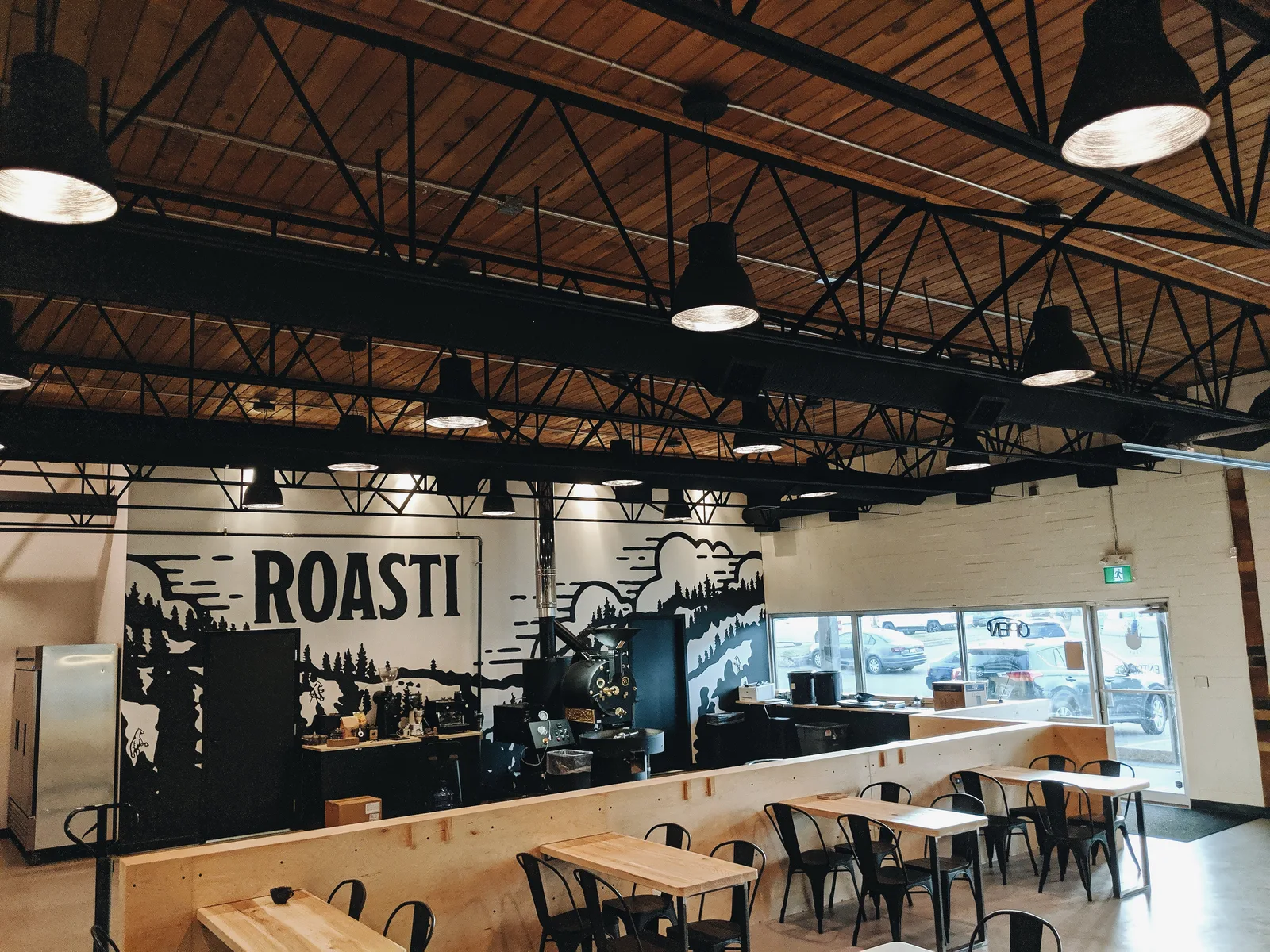 modern industrial café interior with "roasti" signage and wooden ceiling beams., roasti coffee co, sherwood park