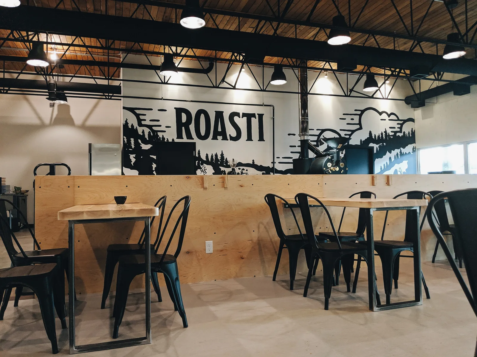 modern coffee roastery interior with industrial ceiling, wooden counter, and black chairs., roasti coffee co, sherwood park