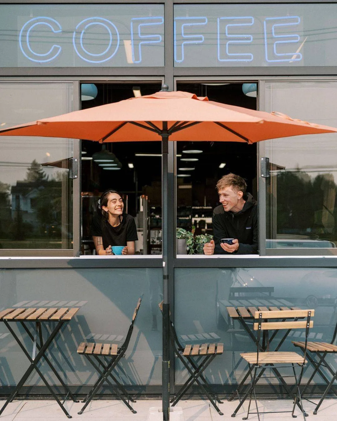 two people enjoying beverages at a modern coffee shop with orange umbrella., rogue wave coffee, edmonton