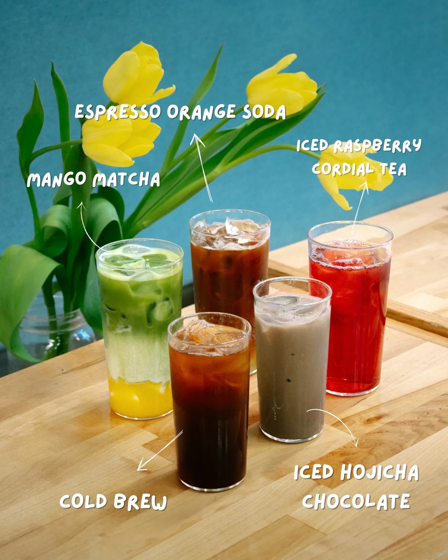 five iced beverages labeled with names displayed on wooden table with yellow flowers., rogue wave coffee, edmonton