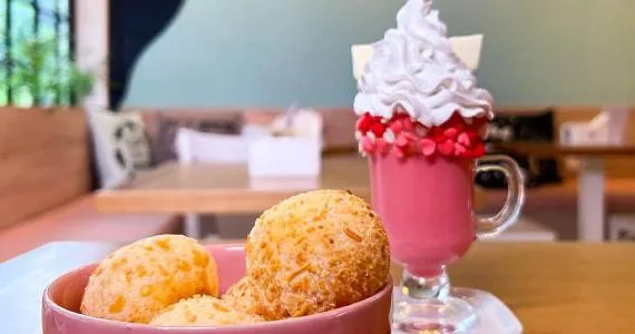 golden pastries in pink bowl beside pink beverage with whipped cream topping., ronron cat café, são paulo