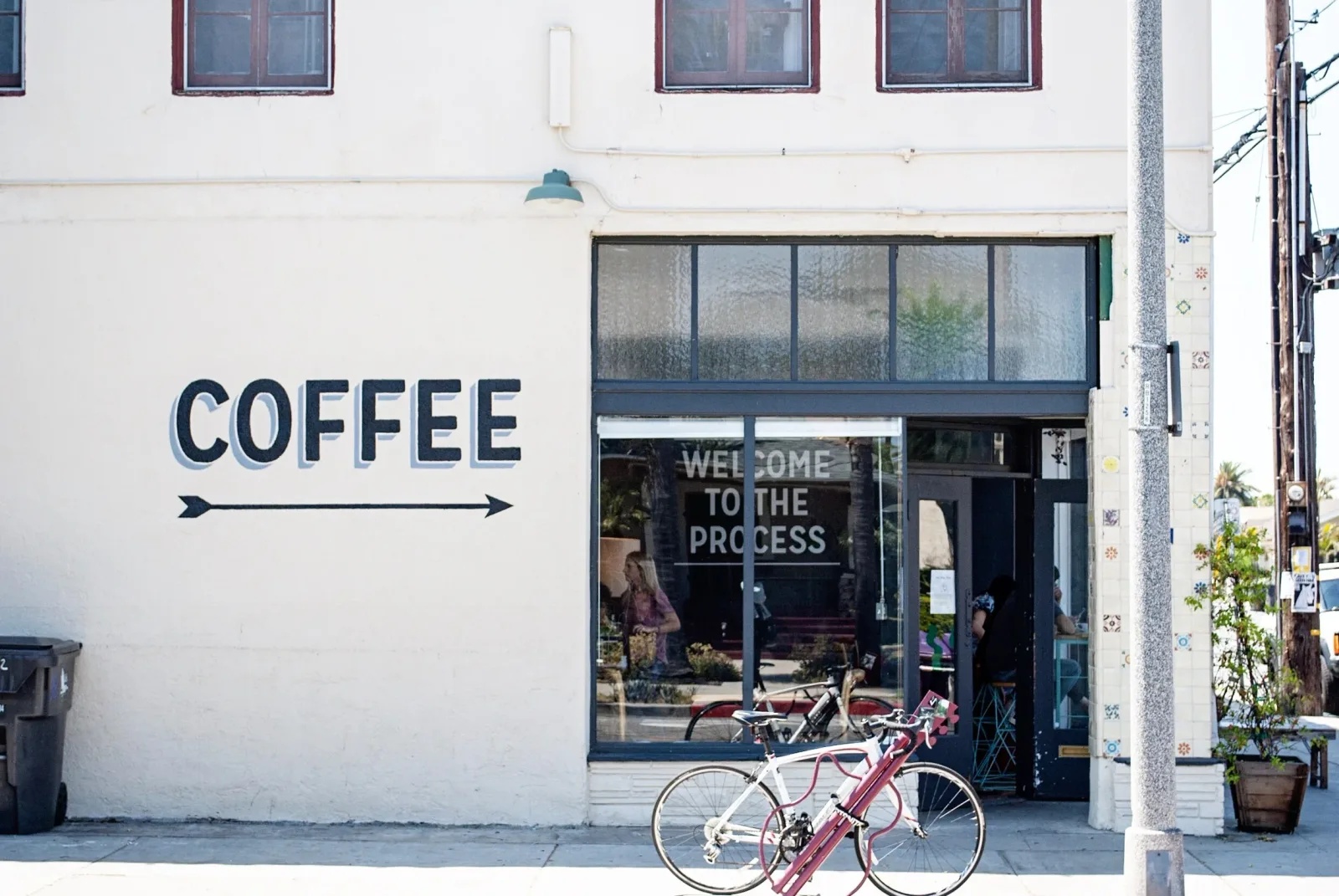 coffee shop storefront with arrow sign and bicycles parked outside entrance., rose park roasters, los angeles