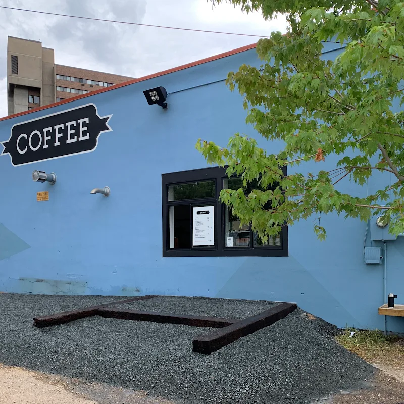 blue coffee shop with service window, black framing, and green foliage overhead., roundtable coffee works, saint paul