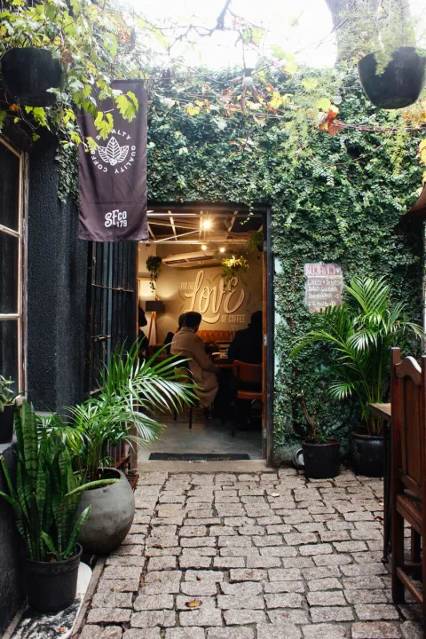ivy-covered entrance to intimate cafe with warm lighting and lush greenery., royalty café, curitiba