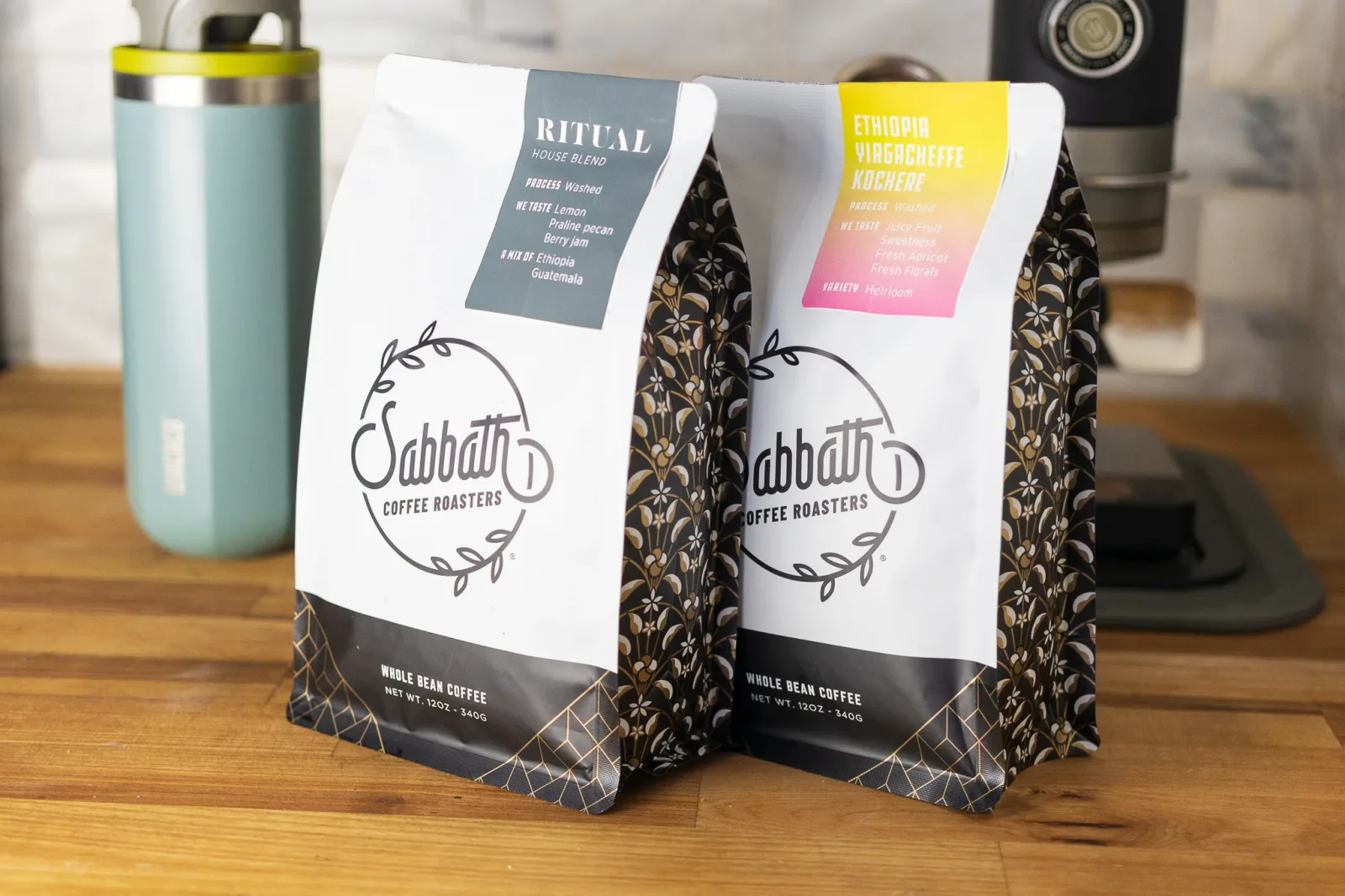 two sabbath coffee roasters bags displayed on wooden counter with thermos., sabbath coffee, clawson