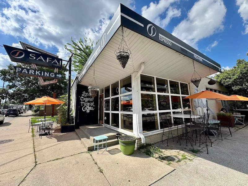 small corner café with white exterior, orange umbrellas, and outdoor seating area., safai coffee shop, kentucky