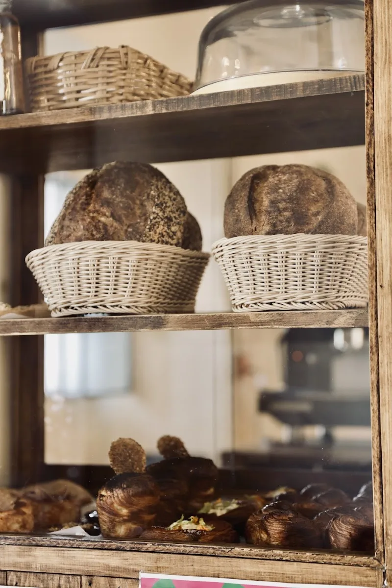 bakery display case with artisan breads in wicker baskets and pastries., sagrado filemón i pan y café, de juárez