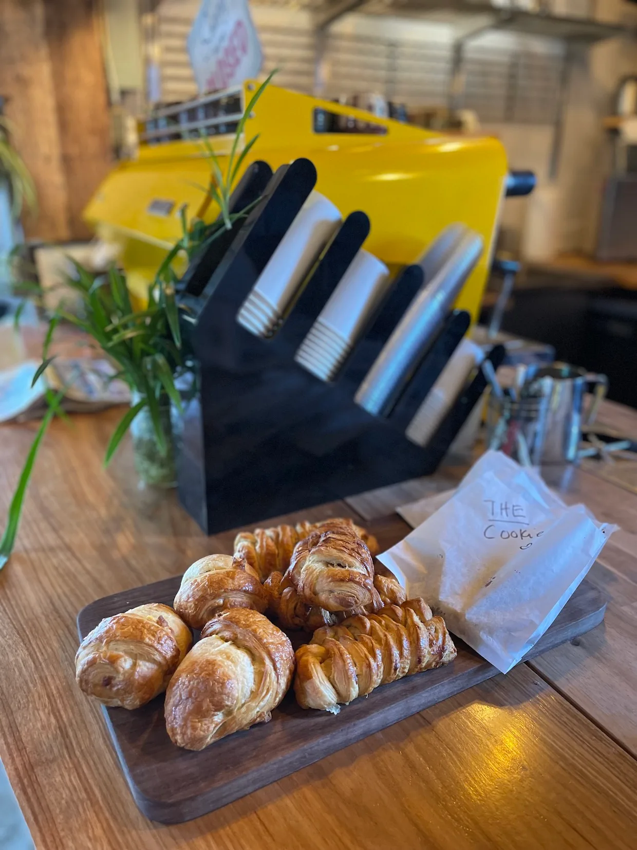 croissants displayed on wooden board with pastry label and yellow espresso machine background., salto coffee, boulder